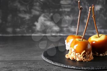 Delicious caramel apples with tree branches on slate plate�