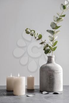 Burning candles and vase with eucalyptus branches on grey table�