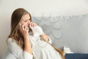 Young pregnant woman talking by phone and crying because of mood change�