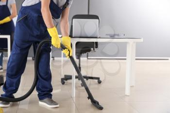 Janitor hoovering floor in office�