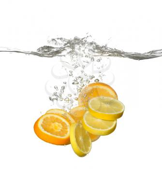 Falling of cut citrus fruits into water on white background�