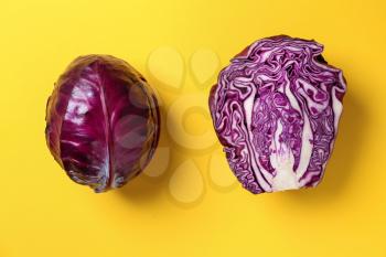 Whole and cut purple cabbages on color background�