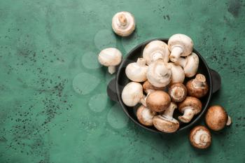 Pan with fresh mushrooms on color table�