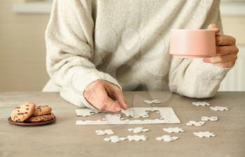 Woman assembling puzzle on table�