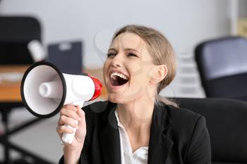 Young businesswoman using megaphone in office�