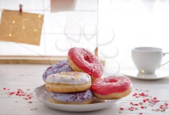 Plate with tasty doughnuts on white wooden table�