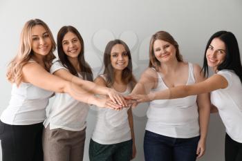 Beautiful young women putting hands together on light background. Concept of body positivity�