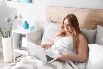 Beautiful plus size girl with laptop resting at home. Concept of body positivity�