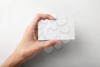 Female hand with blank business card on light background�