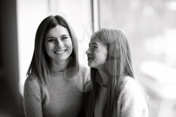 Black and white portrait of happy mother and daughter near window�