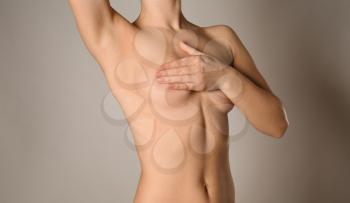 Naked woman on grey background. Concept of breast augmentation�