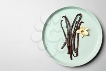 Plate with aromatic vanilla sticks on white background�