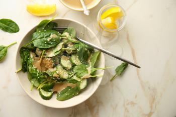 Tasty vegetable salad with tahini in bowl on light table�