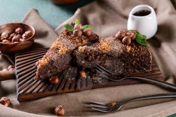 Wooden board with pieces of tasty chocolate cake on table�