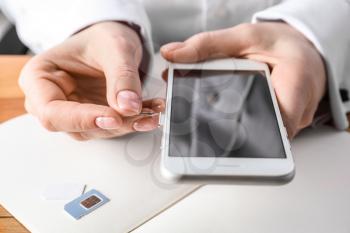 Woman opening sim card slot with key, closeup�