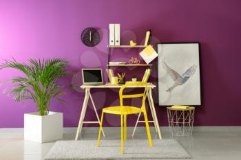 Stylish workplace with modern laptop near color wall�