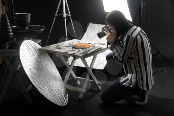 Young woman taking picture of tasty pasta in professional photo studio�