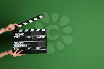 Female hands with cinema clapperboard on color background�