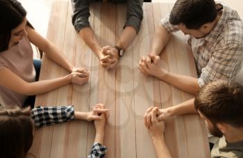 Group of people praying at table�