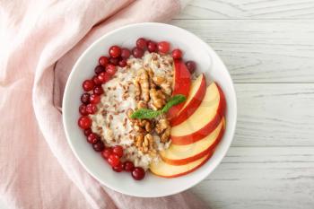 Bowl with tasty oatmeal on white table�