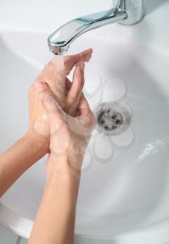 Woman washing hands in sink�