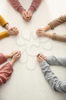 Group of people praying together at table�