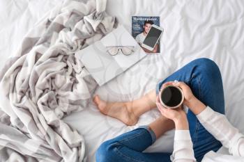 Young woman drinking coffee on bed in morning�
