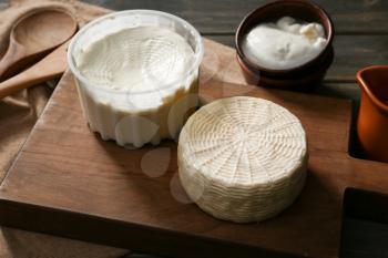 Wooden board with tasty cheese on table�