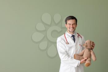 Pediatrician with toy bear on color background�