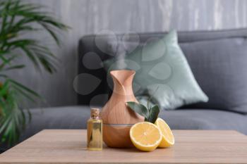 Aroma oil diffuser and citrus fruit on table in room�