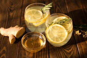 Glasses of fresh lemonade, honey and ginger on wooden table�