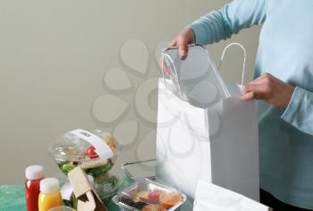 Worker of food delivery service packing order for customer�
