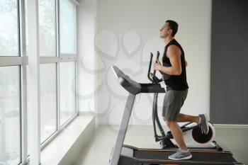 Sporty young man on treadmill in gym�