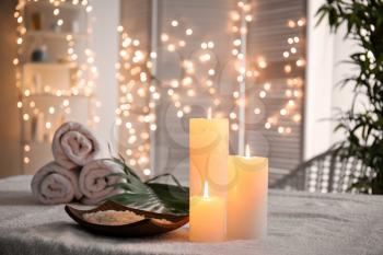 Plate with sea salt and burning candles on table in spa salon�