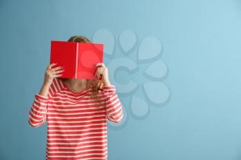 Schoolgirl with book on color background�