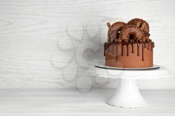 Stand with sweet chocolate cake on white table�