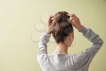 Young woman with hair bun on color background�