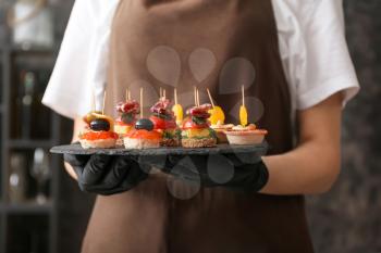Chef holding slate plate with tasty canapes, closeup�