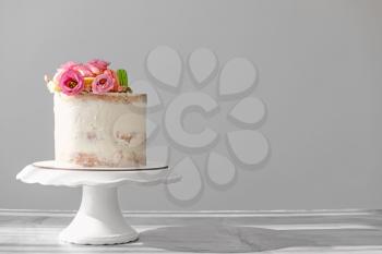 Sweet cake with floral decor on grey background�