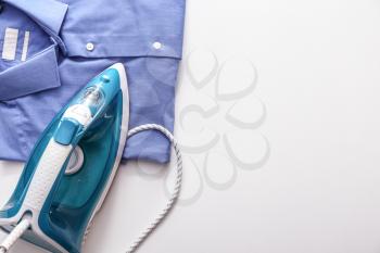 Iron with clean clothes on white background�