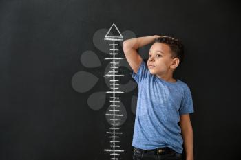 African-American boy measuring height near dark wall�