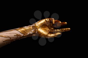 Female hand with golden paint against dark background�