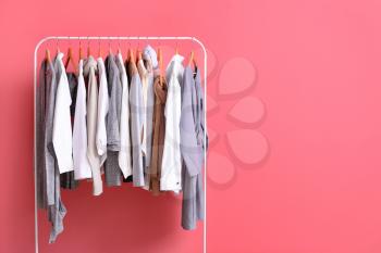 Rack with stylish clothes on color background�