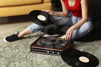 Young woman with old record player and vinyl discs at home�