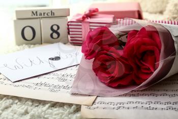 Bouquet of beautiful roses, note sheets and calendar with date 8 MARCH on soft plaid�