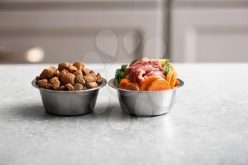 Bowls with dry and fresh pet food on table�