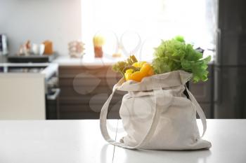 Eco bag with fresh vegetables on table in kitchen�