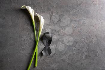 Black funeral ribbon and flowers on grey background�