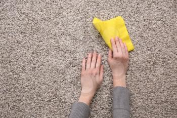 Female hands with rag on carpet�