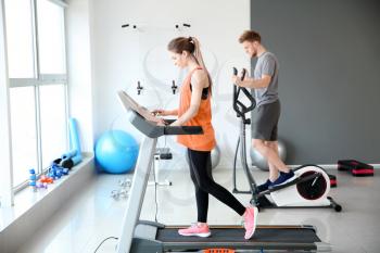Sporty young people training on machines in gym�